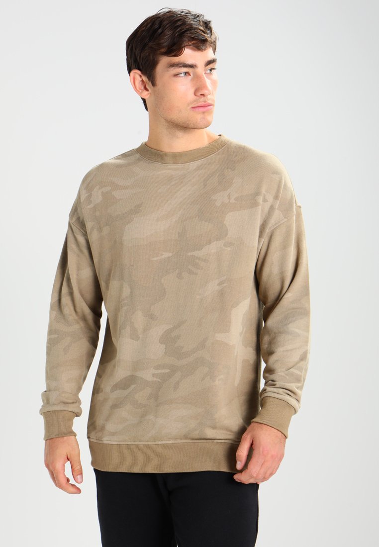 Beige camouflasjegenser med lange ermer, ribbestrikket rund hals og hem, myk stofftekstur og avslappet passform.