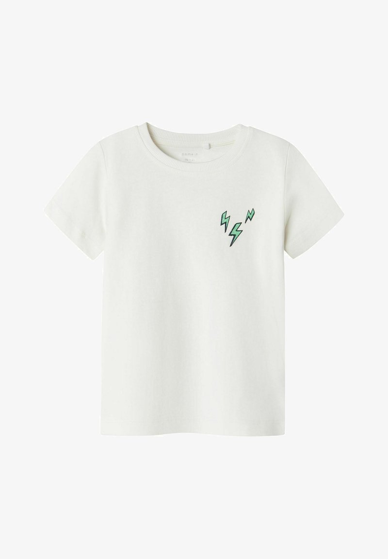 Camiseta de algodón blanca con mangas cortas, que presenta un patrón de rayo verde en la parte izquierda del pecho. Textura suave, cuello redondo.