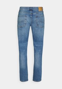 Slim-fit blå jeans i denim, med medelhög midja, två bakfickor med sömdekoration och en läderlogotyp.