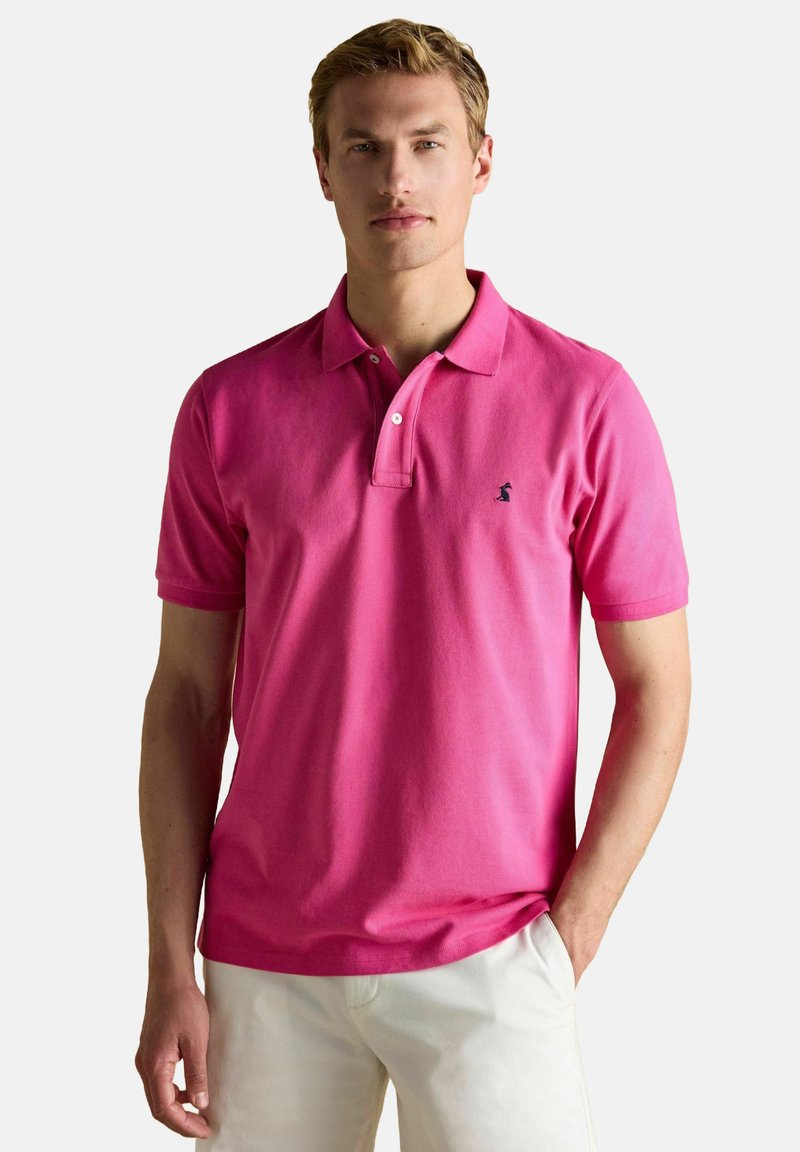 Roosa polo särk, mis on valmistatud puuvillast, klassikalise krae, kahe nupuga ja väikese musta logoga vasakul rinnaosal. Lühikesed varrukad ja lõdvendatud istuvus.