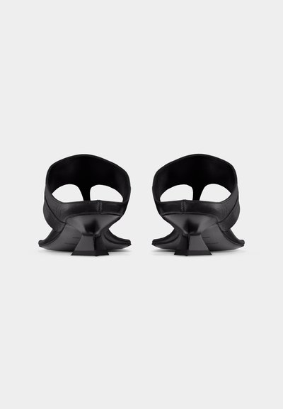 Ζευγάρι μαύρων γυναικείων παπουτσιών με ψηλό τακούνι, ανοιχτή φτέρνα και λαξευτά τετράγωνα τακούνια, εμφανίζεται από πίσω σε λευκό απλό φόντο.