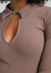 Ribbade långärmade toppar i mauve med en knäppbar krage och ett nyckelhålsdessign i halsen, som visar en mjuk, texturerad tyg.