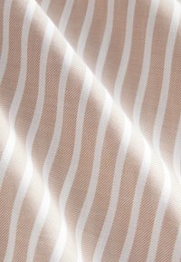 Tissu pêche clair avec des rayures blanches alternées, présentant un tissage fin et texturé. Surface lisse avec un léger éclat.