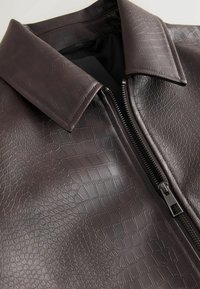 Bruine faux leren jasje met een gestructureerd krokodillenpatroon, grote kraag en een ritssluiting aan de voorkant. Glad interieurvoering.