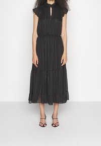Robe midi noire avec un décolleté en trou de serrure, des manches volantées et un ourlet à volants. Fabriquée en tissu texturé avec une légère brillance. Portée avec des sandales noires à lanières.