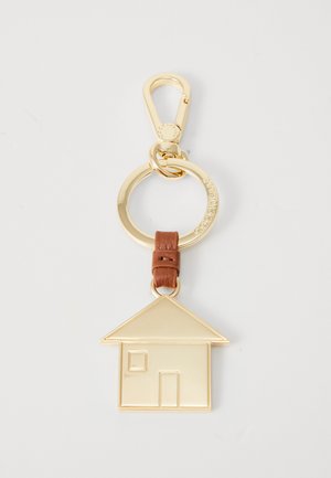 Gold metal keychain with house-shaped charm, brown leather strap, and circular ring with engraved text on a white background.
