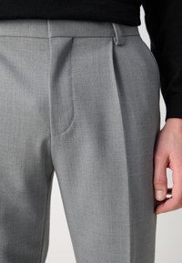 Gray pleated trousers made of textured fabric, featuring a straight cut and side pockets, with a smooth waistband and tailored fit.