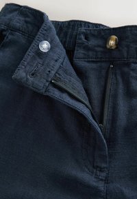 Pantaloni bleumarin cu fermoar, închidere cu nasture și talie elastică. Material neted cu o textură subtilă.