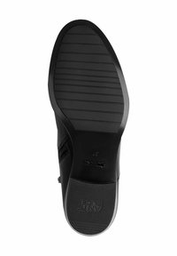 Suela de zapato negra con un patrón de agarre texturizado y estrías. El lateral tiene un acabado liso. Logo de la marca visible cerca del talón y un número de talla presente.