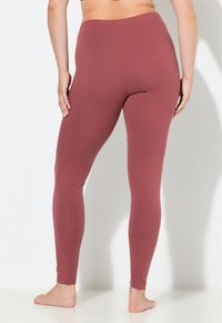 Leggings color marrone scuro con una texture liscia, vita elasticizzata e design aderente, mostrati da dietro, con una finitura semplice e senza cuciture.