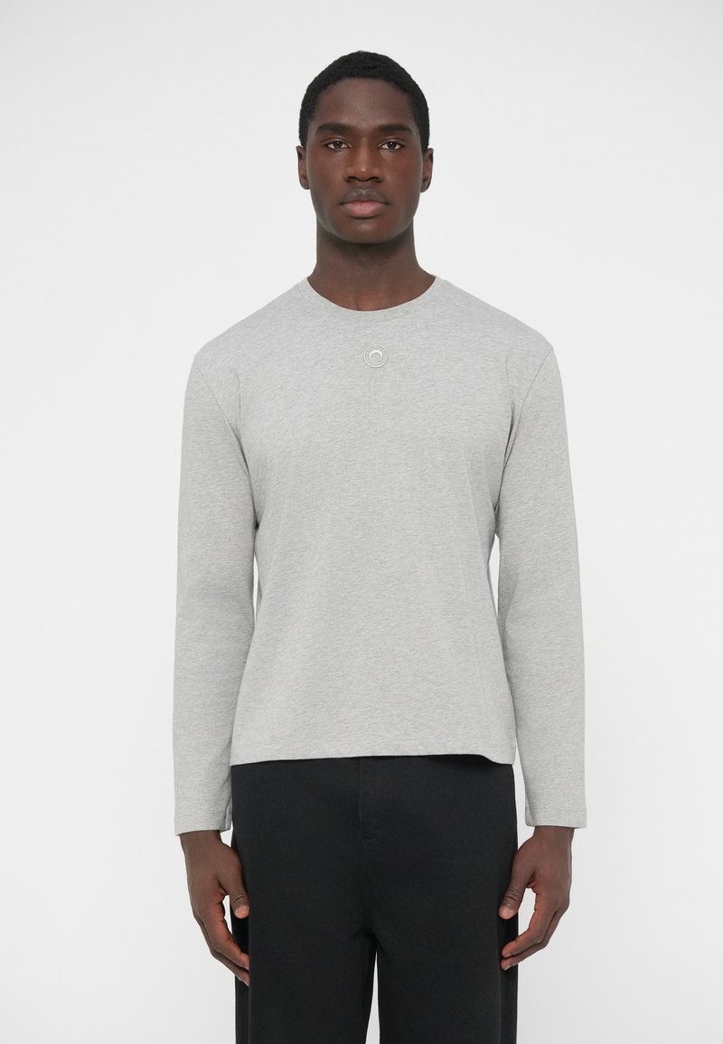 Sivá dlhýrukávová bavlnená tričko s okrúhlym výstrihom a zaobleným lemom. Na hrudi má malý kruhový detail.