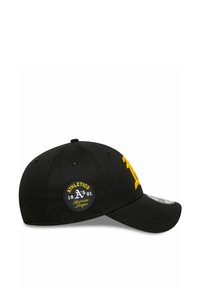 Gorra de béisbol negra con visera curva, que presenta un logo bordado amarillo en la parte delantera y un parche redondo en el costado.