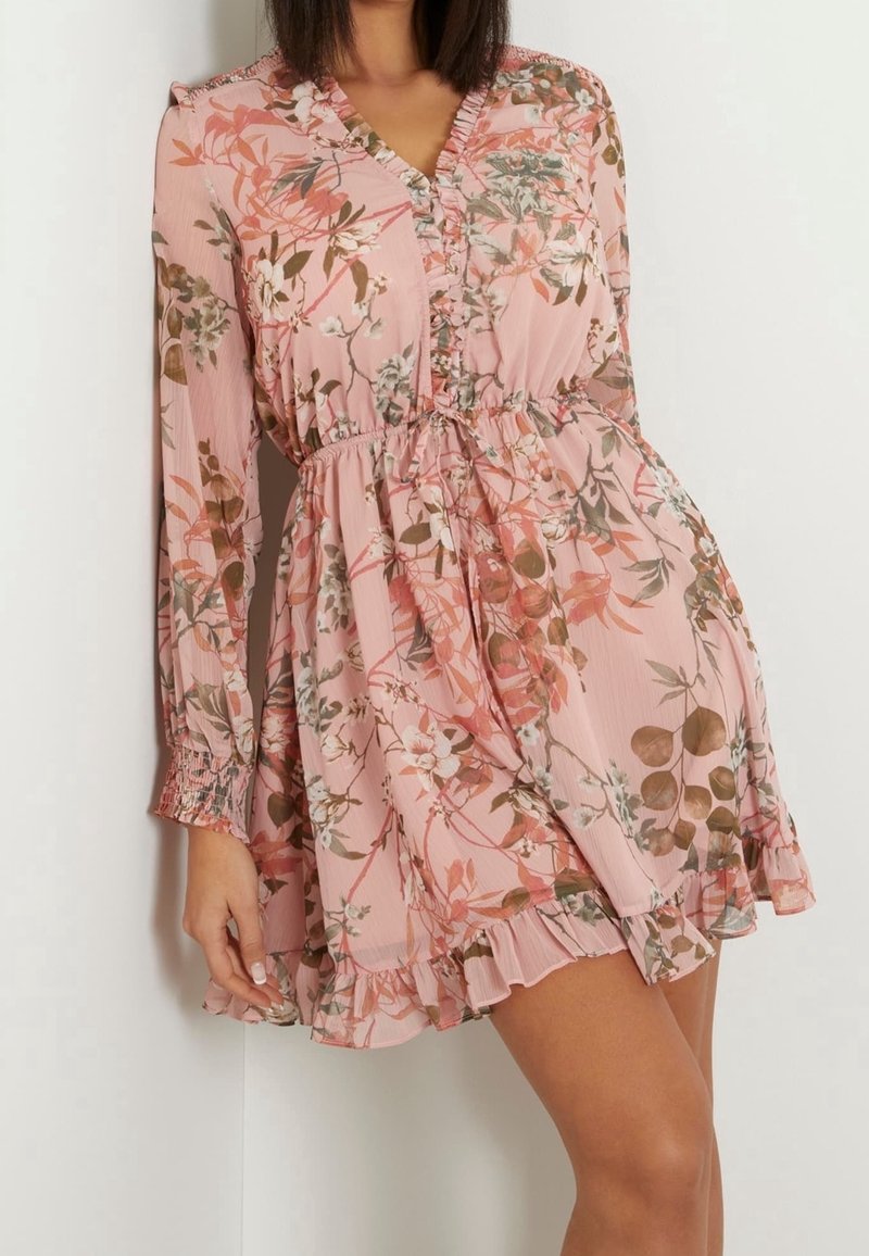 Long-sleeved pink dress with floral pattern, ruffled hem, and empire waist. Made from lightweight, textured fabric with a v-neckline.