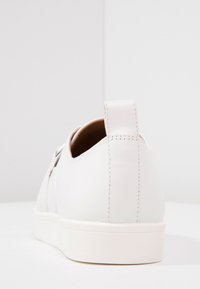 Vita lädersneakers med en slät yta, låg profil, rund tå och en flik vid hälen. Minimalistisk design, inga synliga mönster eller accenter.