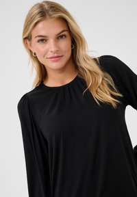Black long-sleeve top with a gathered neckline and slightly puffed shoulders, featuring soft fabric and a smooth texture.