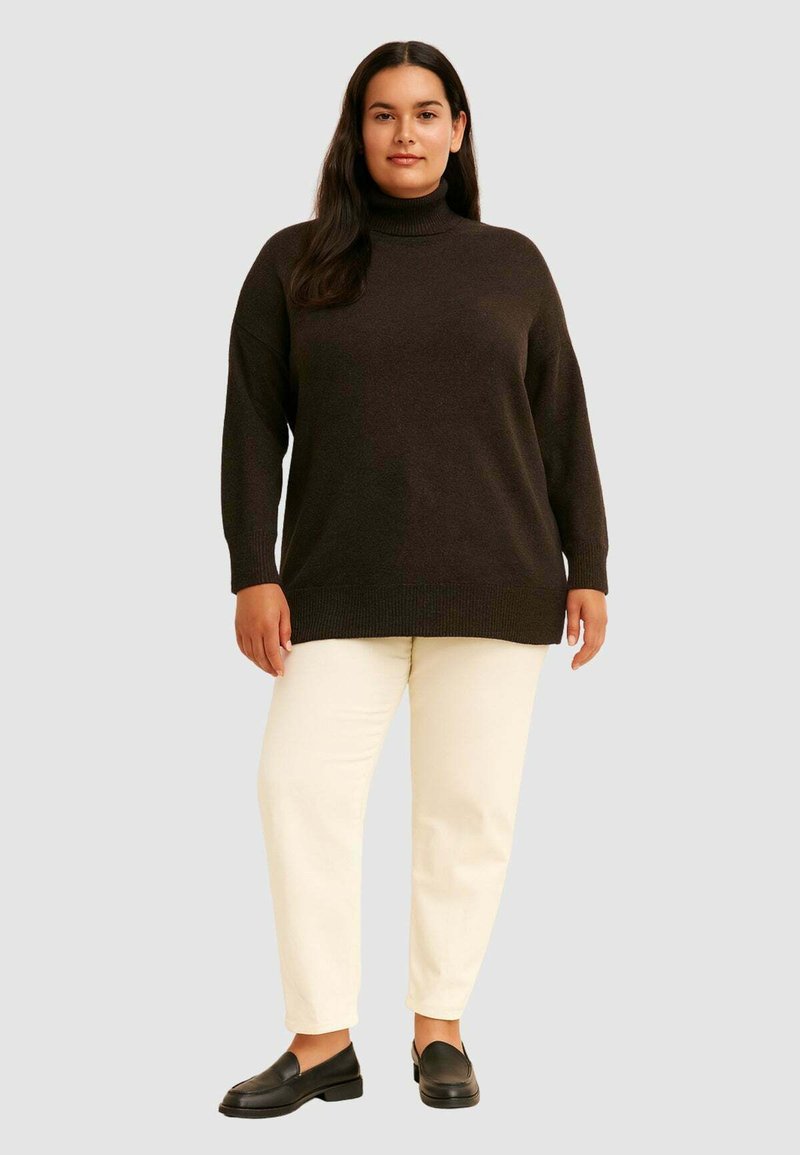 Mørkebrun turtleneck sweater med en løs pasform, ribbede ærmer og kant. Kombinationen med cremafarvede straight-leg bukser og sorte loafers.