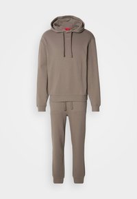 Set format hoodie maro cu pantaloni de trening asortați. Material moale, croială relaxată, șnur ajustabil la glugă, manșete ribbate, branding minimal.