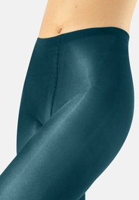 Legginsy w kolorze ciemnego teal z wysokim stanem, wykonane z błyszczącego, elastycznego materiału, charakteryzujące się gładką teksturą i dopasowanym krojem, zaprojektowane z myślą o komforcie i zakryciu.