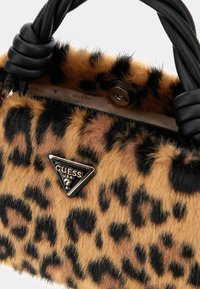 Torebka z futrzanym nadrukiem w cętki lamparta, wyposażona w czarny supełkowany uchwyt i trójkątną plakietkę z logo. Miękka tekstura z kontrastującymi wzorami.