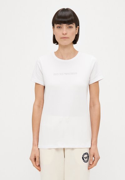 Weißes Baumwoll-T-Shirt mit kurzen Ärmeln, mit einem dezenten, gestickten "EMPORIO ARMANI"-Logo auf der Brust. Glatte Textur, klassischer Schnitt.