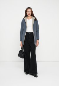 Padded jacket in blue with beige lining, white shirt, black wide-leg jeans, and a small black bag. Solid colors, minimalistic design.