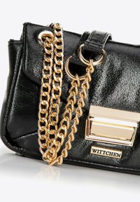 Sac à main en simili cuir noir avec une finition texturée, une bandoulière en chaîne dorée et un accent en métal doré portant le nom de la marque "Wittchen."