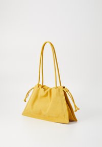 Sac à main en daim jaune avec fermeture à cordon, forme triangulaire et deux poignées allongées. Texture lisse, design minimaliste.