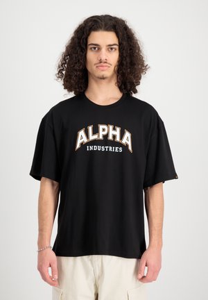 Schwarzes, oversized T-Shirt aus Baumwolle. Mit großem weißen und orangen "ALPHA"-Schriftzug, darunter "INDUSTRIES". Kurze Ärmel, Rundhalsausschnitt.