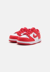 Red and white Nike shoes featuring leather material, rounded toe, lace-up closure, perforated toe box, and logo detail on the side.