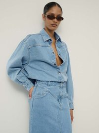 Hele sinine teksapaita nupukrae ja laia lõikega, rinnataskuga; sobib kokku sobiva helesinise teksaseelikuga.