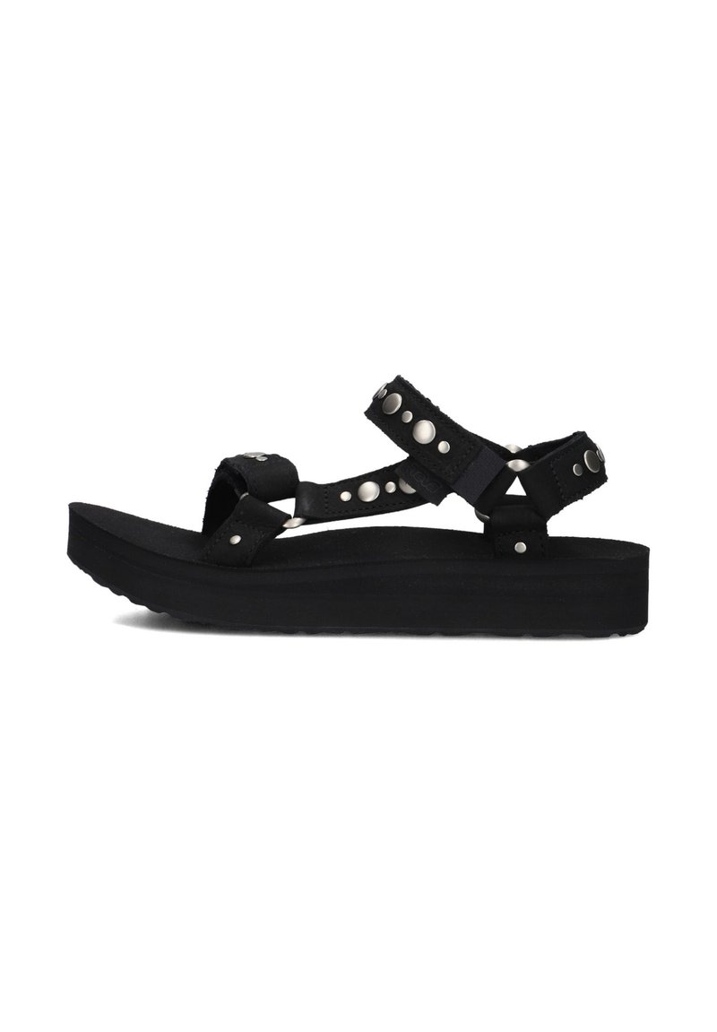 Zwarte platform sandalen met verstelbare banden, zilveren studs en een gestructureerde zool. Het materiaal lijkt duurzaam en zacht te zijn.