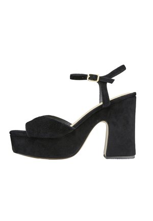 Sandales à plateforme en suède noir avec un bout rond, un épais talon haut, une lanière à la cheville et des détails en métal doré. Matériau texturé, design élégant.