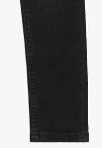 Jeans de denim negro con un ajuste slim, que presentan una textura suave, costura en la costura lateral y un dobladillo sin desgastes ni adornos.