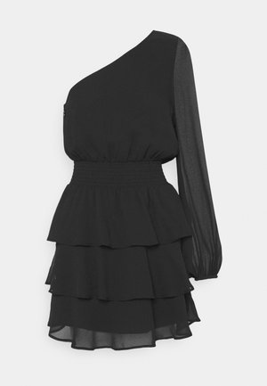 Robe noire asymétrique avec une manche longue transparente, taille élastique et jupe à volants étagés.