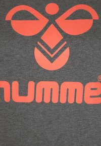 Tela gris con un gran logo en un vibrante color rosa que presenta un diseño simétrico de círculos y líneas, mostrando de manera destacada la palabra "humme."