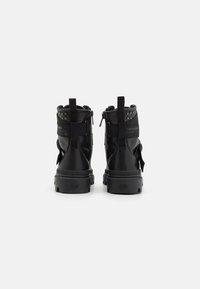 Czarne botki za kostkę wykonane z gładkiej skóry z teksturowaną podeszwą, wyposażone w zamki, regulowane paski i ćwieki na pięcie.