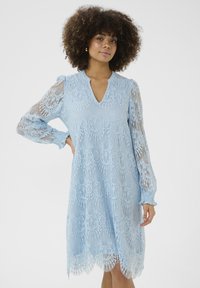 Světle modré krajkové šaty s dlouhými balónovými rukávy, výstřihem do V, květinovými vzory a vroubkovaným lemem. Průsvitná textura s jemnými detaily.