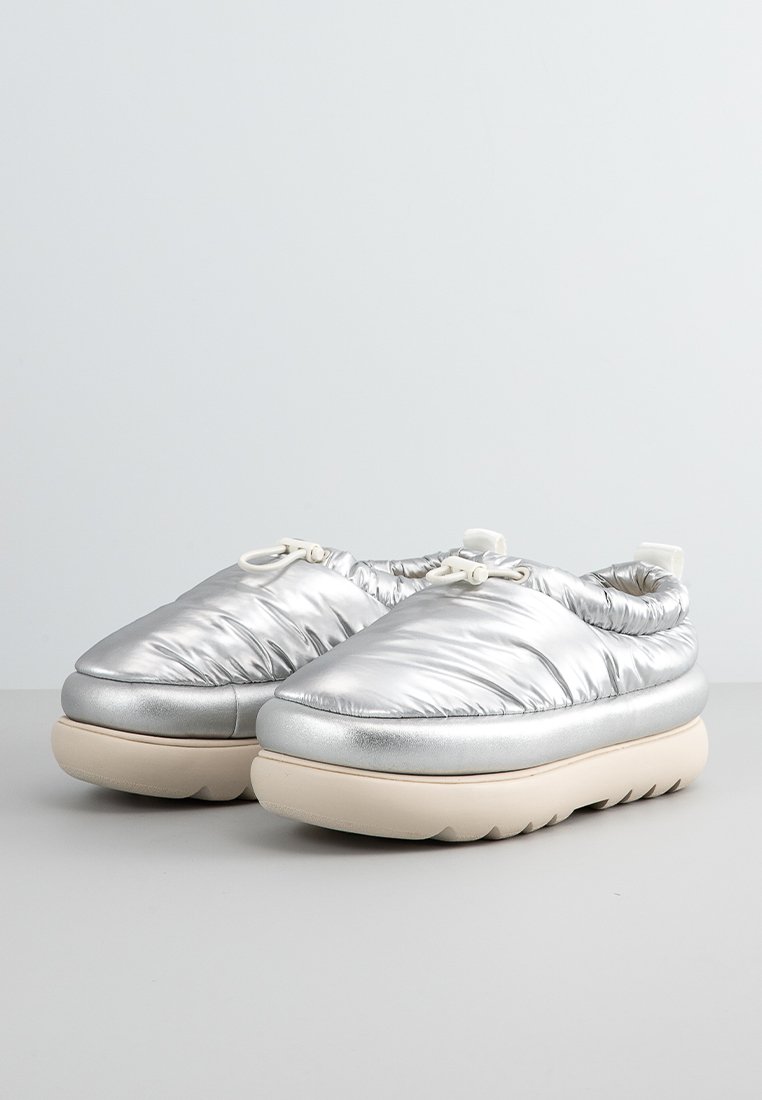 Un paio di scarpe slip-on isolate in metallo argento con suole spesse beige e cordoncino regolabile nella parte superiore.
