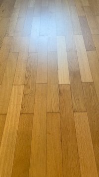 Suelos de parquet de madera marrón clara con tablas rectangulares estrechas dispuestas en un patrón escalonado, mostrando la veta y textura natural de la madera.