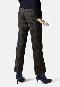 Bruine geruite broek met een rechte snit, textuurstof en hoge taille, gecombineerd met blauwe puntige enkelboots.