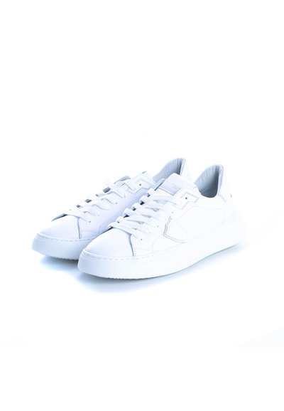 Baskets en cuir blanc avec une texture lisse, bout arrondi, semelle plate et plusieurs œillets pour les lacets. Design minimaliste, sans accents supplémentaires.