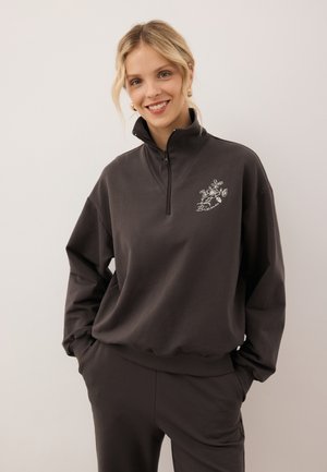 Czarnoszary sweatshirt zapinany na zamek z wysokim kołnierzem, ozdobiony kwiatowym haftem po lewej stronie na klatce piersiowej oraz luźnymi rękawami.