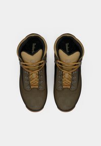 Pruunid matkajalanõud, millel on sametised ja tekstiilist pealsed, beežide aksentide, oranžide paelte ja kummist tallaga, mis tagab haarde.