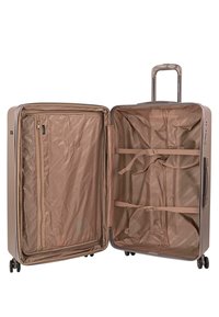 Maleta rígida de color marrón claro, con un interior abierto forrado de tela, bolsillo con cremallera, correas y cuatro ruedas.