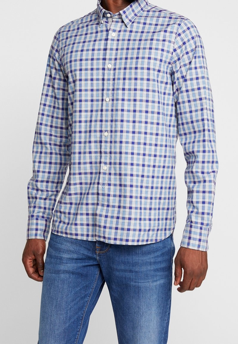 Camicia a maniche lunghe con bottoni, in un motivo scozzese multicolore che presenta blu, verde e bianco. Il tessuto sembra morbido ed è dotato di un colletto standard.