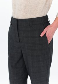 Pantaloni a quadri in tessuto grigio scuro con un delicato motivo a check; dotati di tasche laterali e vestibilità sartoriale. Texture liscia.