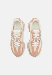 Hellrosa und cremefarbene Sneaker aus Wildleder und Canvas, mit weißen Schnürsenkeln, einer strukturierten Sohle und einem schwarzen Leopardenmusterakzent.