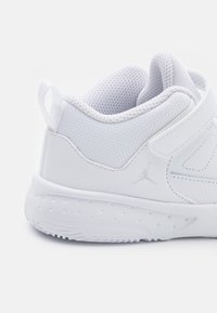 Bílé sportovní boty s texturovaným síťovaným svrškem, hladkými syntetickými akcenty, polstrovaným límcem a gumovou podrážkou s malými perforacemi.