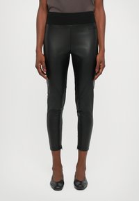 Black faux leather leggings with a high waistband, fitted design, ankle zippers, and a smooth, shiny texture, suitable for various occasions.
