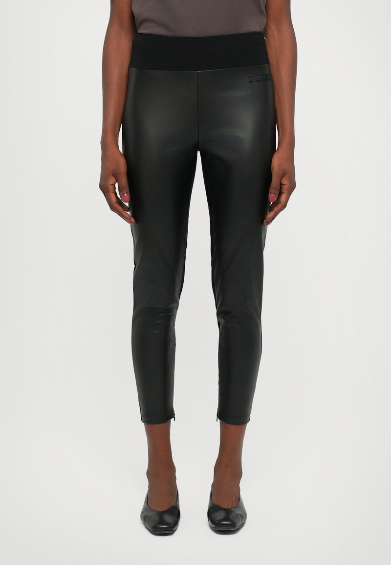 Black faux leather leggings with a high waistband, fitted design, ankle zippers, and a smooth, shiny texture, suitable for various occasions.
